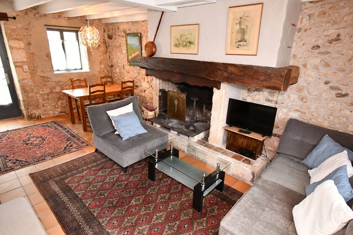 A cozy living room with a stone wall, a fireplace, a sofa, a coffee table, and a TV.