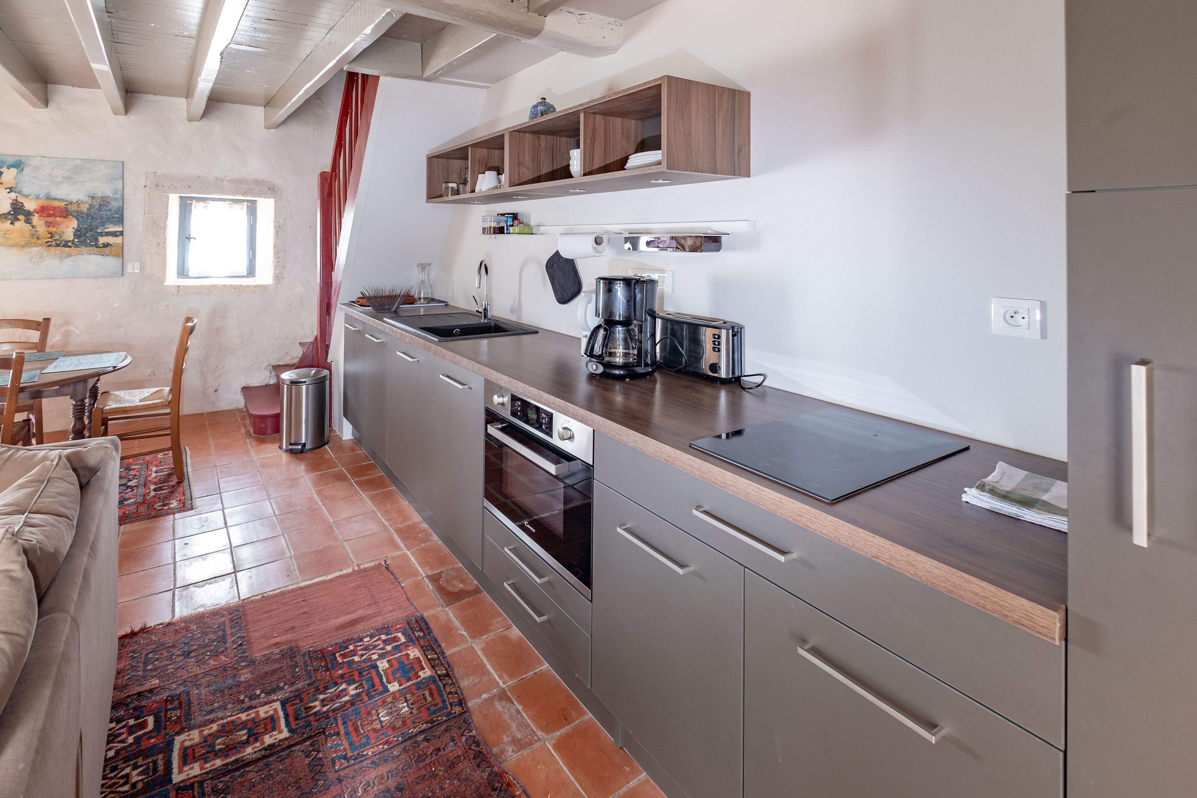 A compact kitchen with a wooden countertop, stainless steel appliances, and a built-in oven.