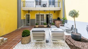 A courtyard with outdoor seating, a small tree, and a building with a yellow facade. - LxWay Poiais de São Bento (Lisbon)