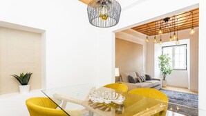 A modern living room with a glass table, yellow chairs, a sofa, and a potted plant. - LxWay Poiais de São Bento (Lisbon)