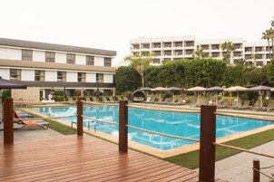 Una piscina al aire libre, sombrillas, sillones reclinables de piscina