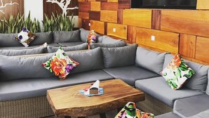 A modern lounge area with a sectional sofa, a wooden coffee table, and a large TV screen. - Mabrouk Hotel And Suites (Agadir)