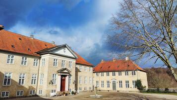 Un grande edificio storico con facciata simmetrica, numerose finestre e un ingresso centrale con porta rossa.