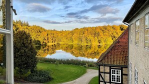 A traditional building with a thatched roof and a view of a lake reflecting yellow foliage. - Skjoldenæsholm Hotel og Konferencecenter (Ringsted)