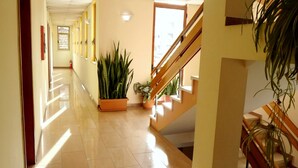 A hotel hallway with a staircase, potted plants, and a fire extinguisher. - Hotel Kruja (Tirana)