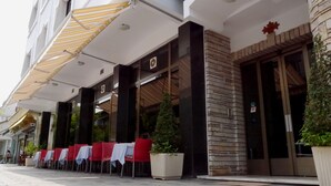 A hotel exterior with outdoor seating, a stone facade, and a large awning. - Hotel Kruja (Tirana)
