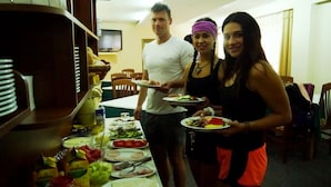 A group of people in a room with a dining table set with various dishes, a television on the wall, and wooden furniture. - Hotel Kruja (Tirana)