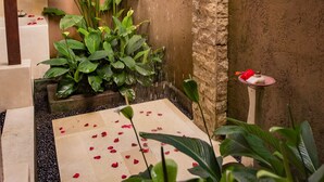 Un espacio de ducha con pared de piedra, techo de madera y exuberante vegetación.