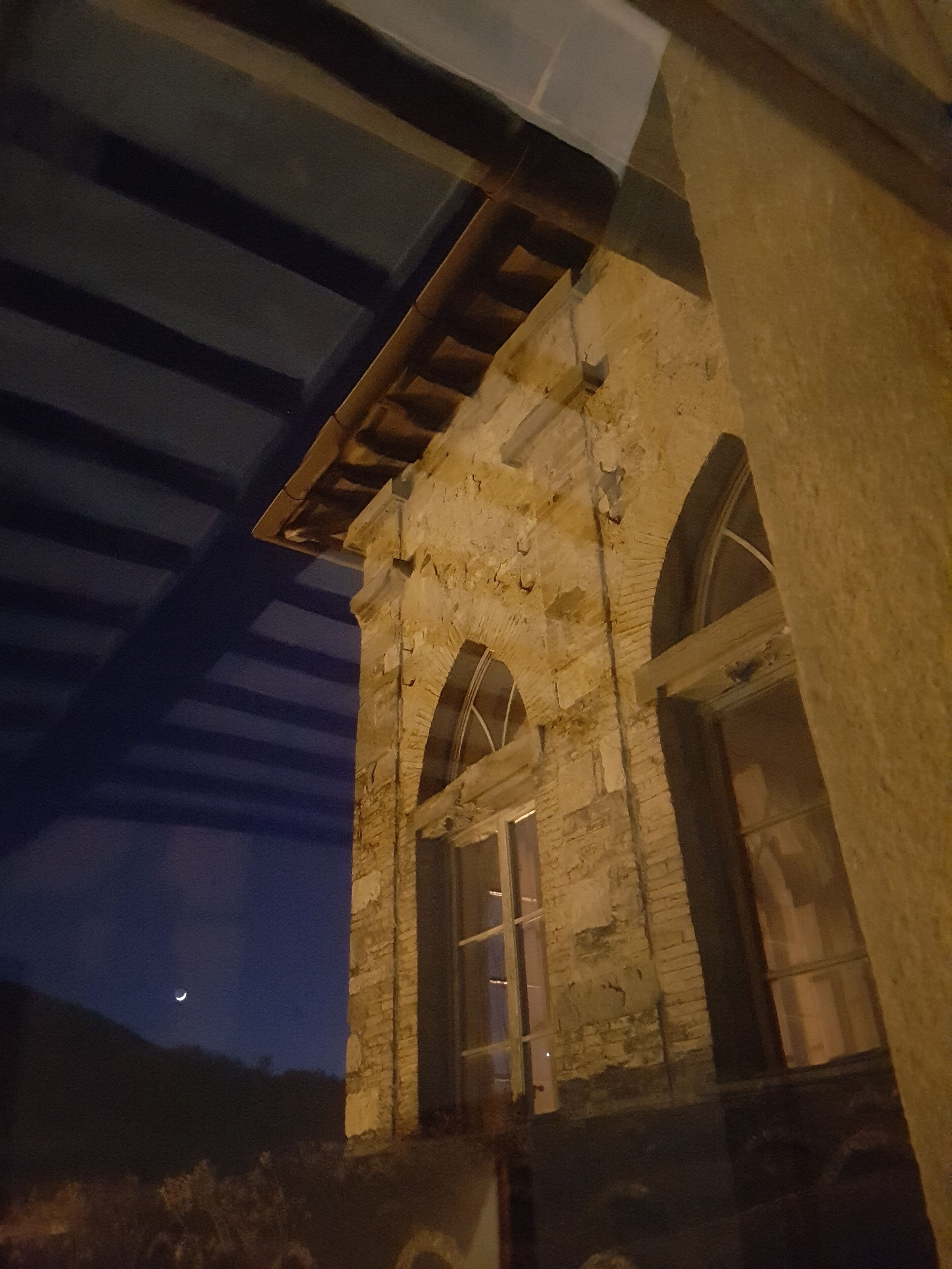 Un bâtiment en pierre doté de fenêtres en arc de cercle et d’une structure en poutres de bois.