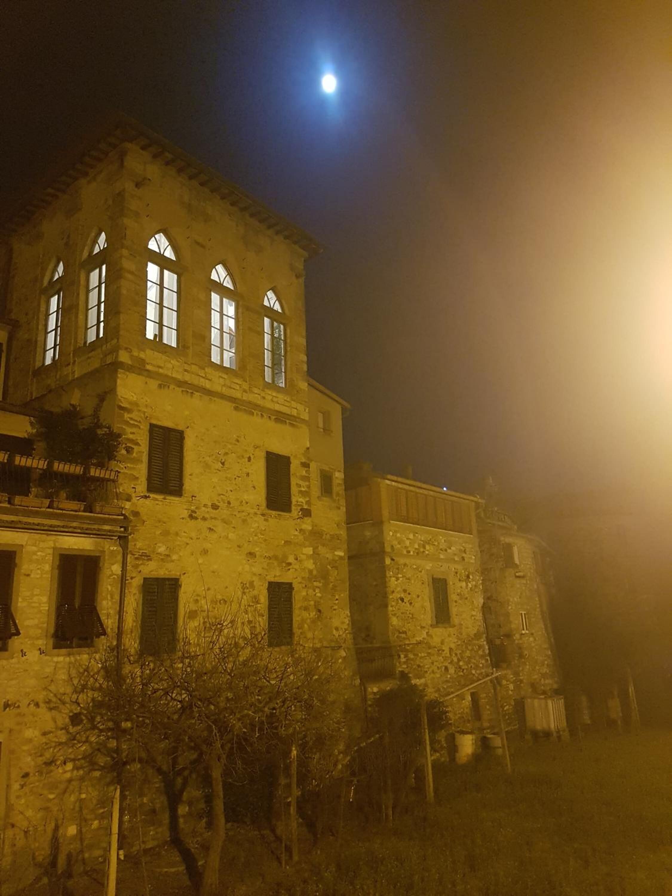 Ein historisches Gebäude mit Bogenfenstern und einem Turm, beleuchtet von sanftem Licht.