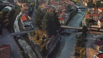 Vista aérea de un pueblo con un río que lo atraviesa, rodeado de edificios con tejados rojos.