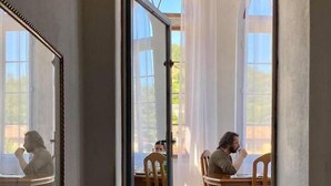 Uma porta estreita que dá para uma sala de jantar com cadeiras e mesas de madeira.
