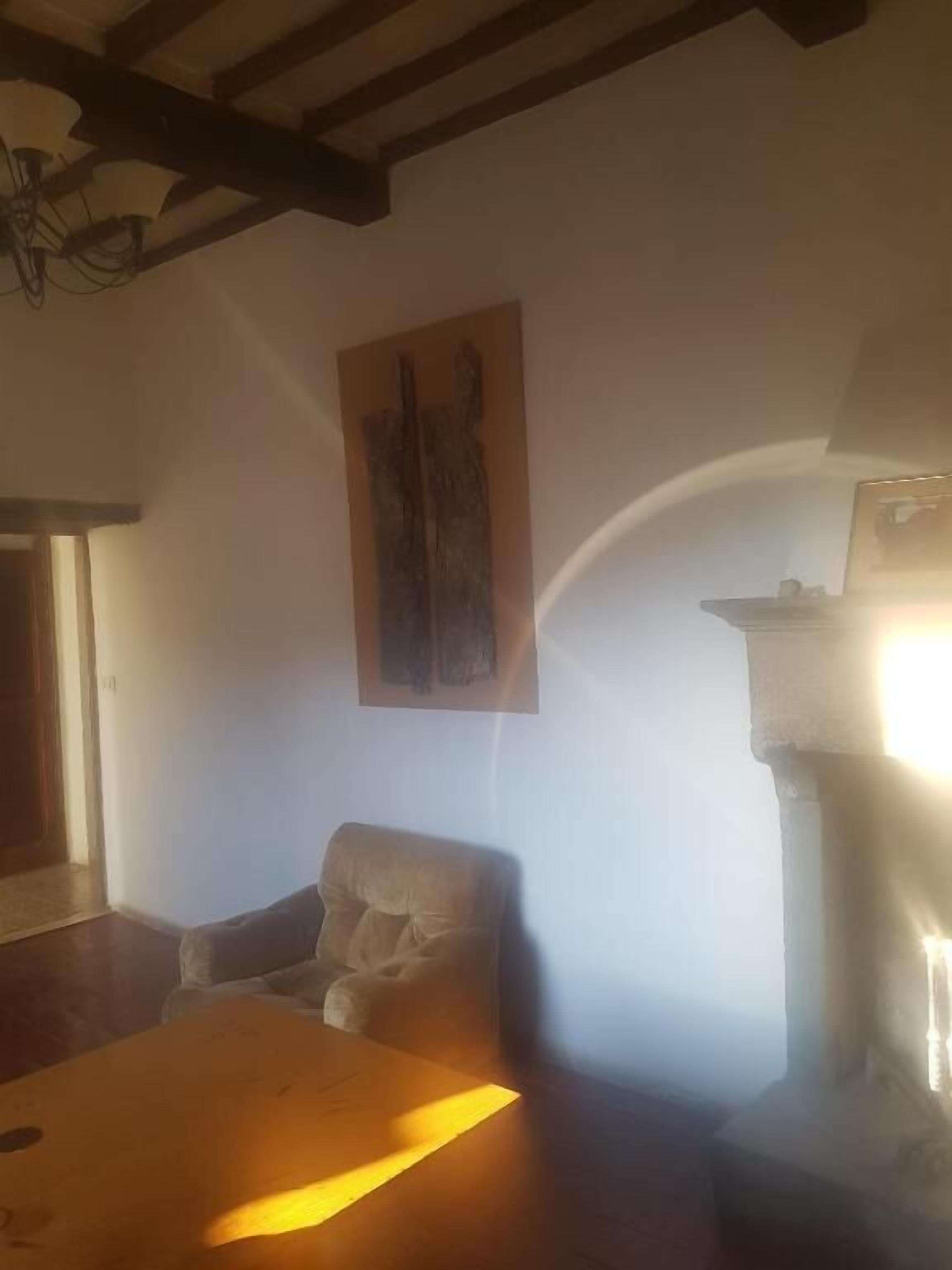 Quarto com uma mesa de madeira, uma cadeira, um quadro na parede e uma lareira.
