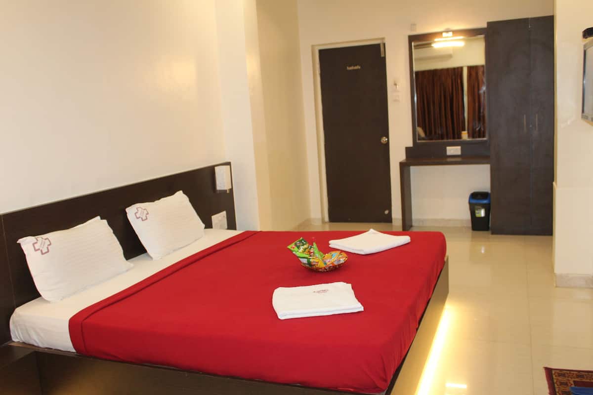 A hotel room with a bed, a small table, a mirror, and a door.
