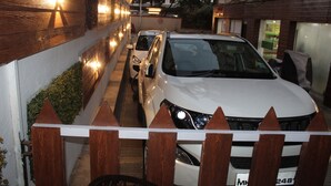 A white SUV parked in a narrow alleyway with wooden fences on either side. - Choice Classic Hotel (Pune)