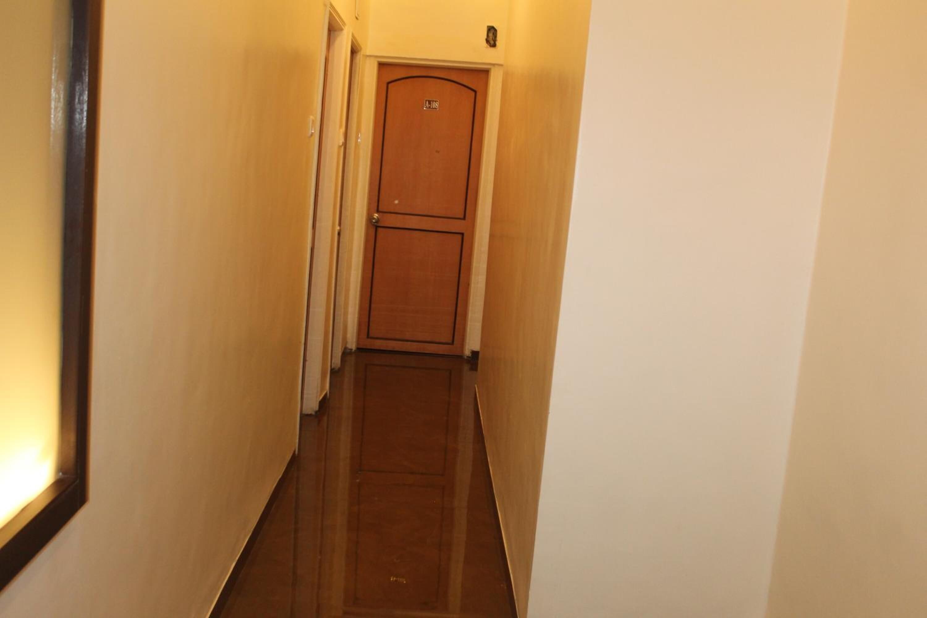 A narrow, well-lit hallway with a wooden door at the end.