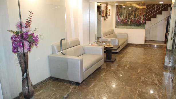 A modern lobby with a marble floor, a sofa, a coffee table, and a decorative vase with flowers. - Choice Classic Hotel (Pune)