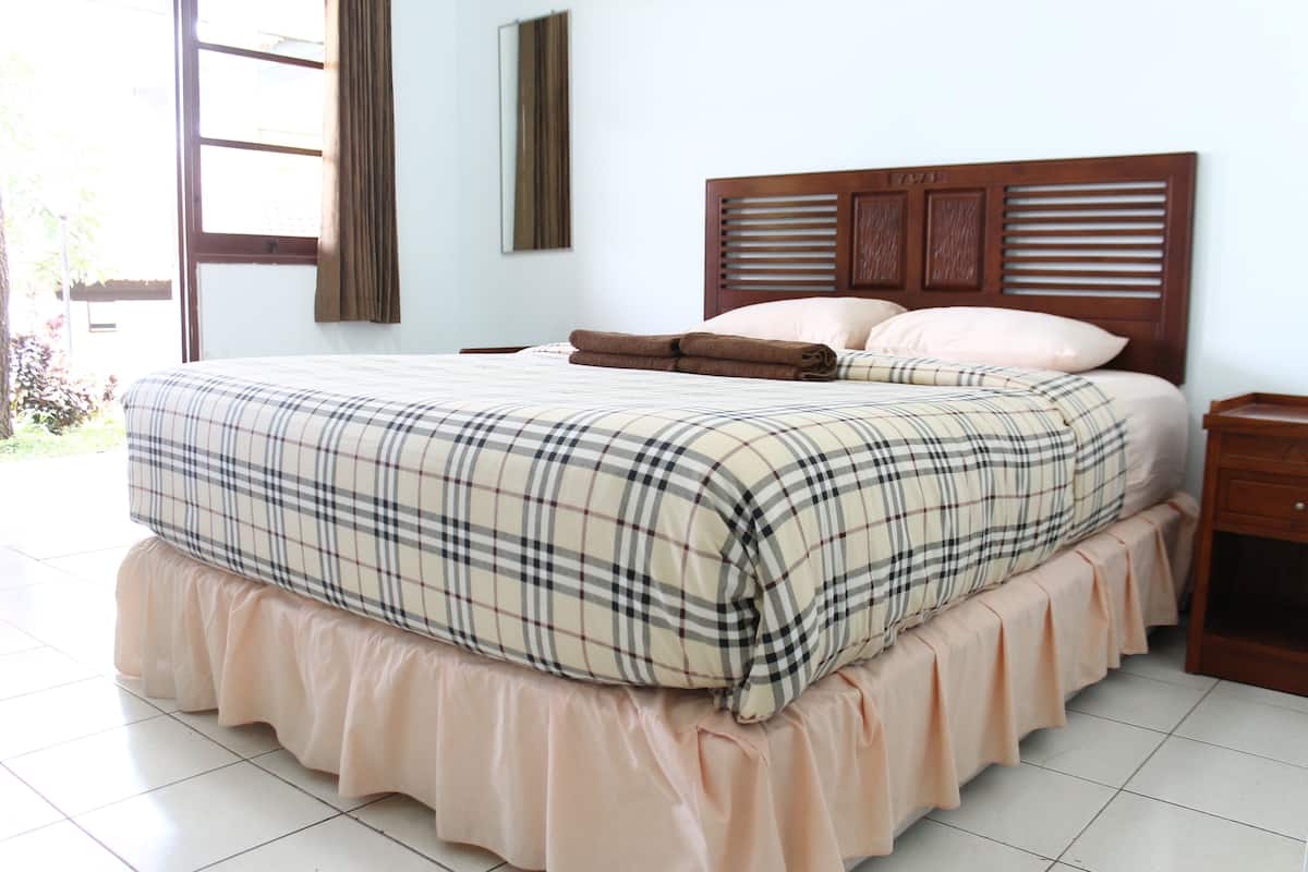 Una cama bien hecha con una colcha escocesa y cabecera de madera.