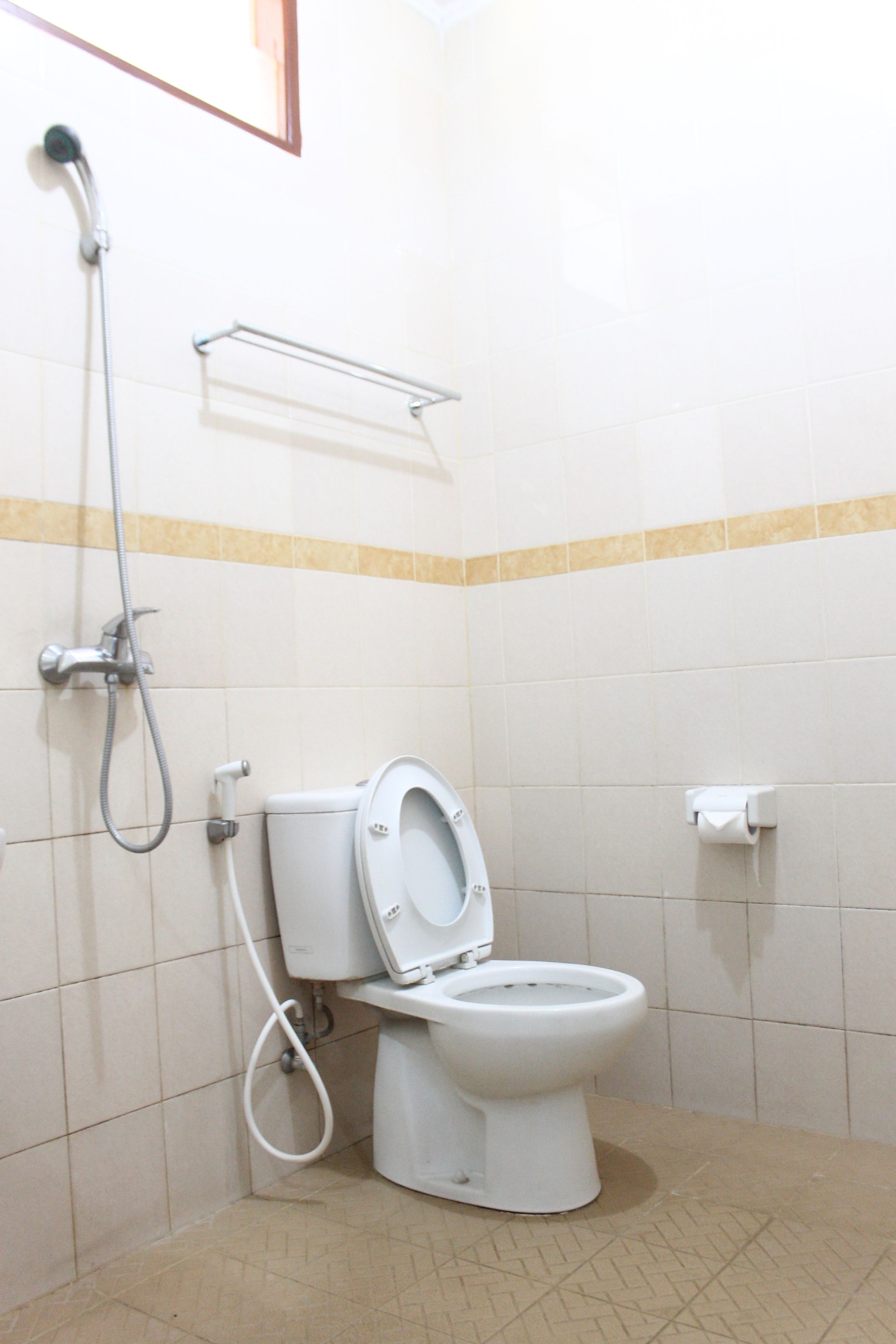 A small, clean bathroom with a toilet, a shower, and a towel rack.