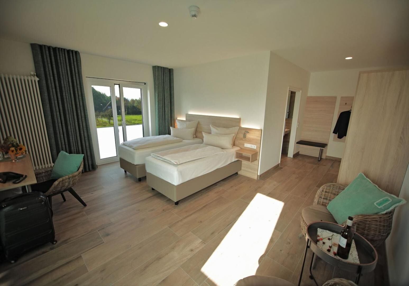 A modern hotel room with two beds, a desk, and a view of the outdoors.