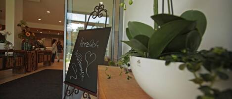 A reception area with a welcome sign, a potted plant, and a view into the interior.