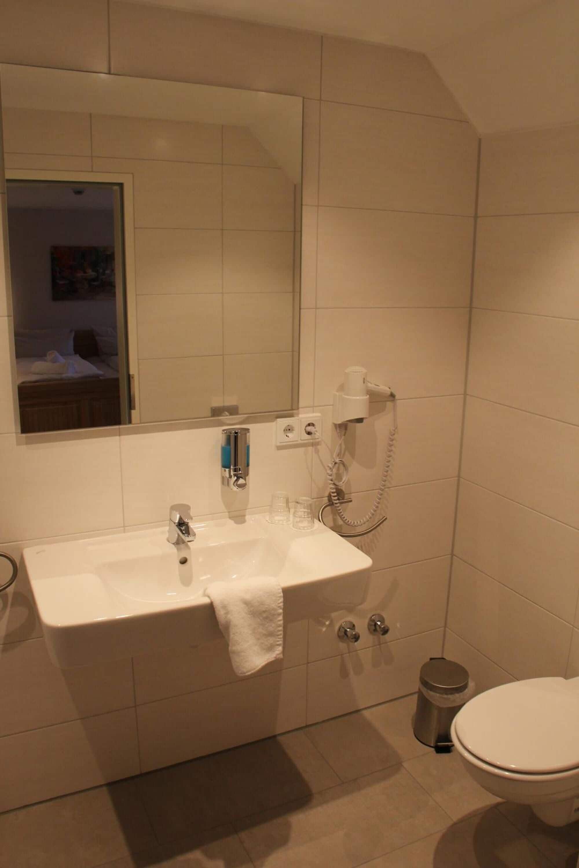 Een badkamer met een wit wastafel, spiegel en toilet.