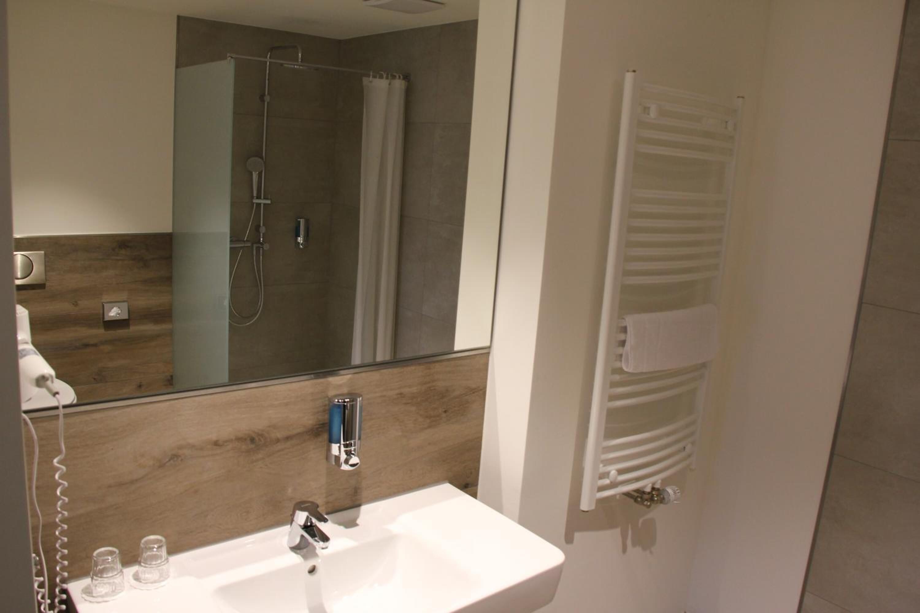 Un baño moderno con cabina de ducha de vidrio, un lavabo blanco y un perchero para toallas.