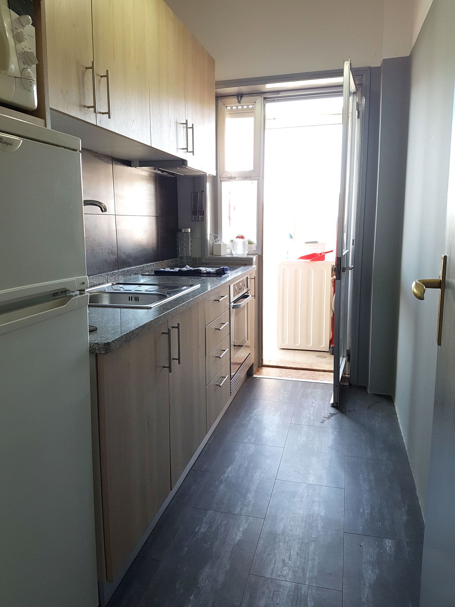 A kitchen with wooden cabinets, a stainless steel sink, and a refrigerator.