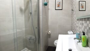 A bathroom with a glass-enclosed shower, a white sink with a green soap dispenser, and a toilet. - Apartamento À Cedofeita (Porto)