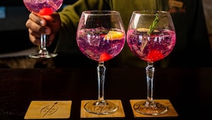 To cocktails på en bardisk med en bartender i baggrunden.