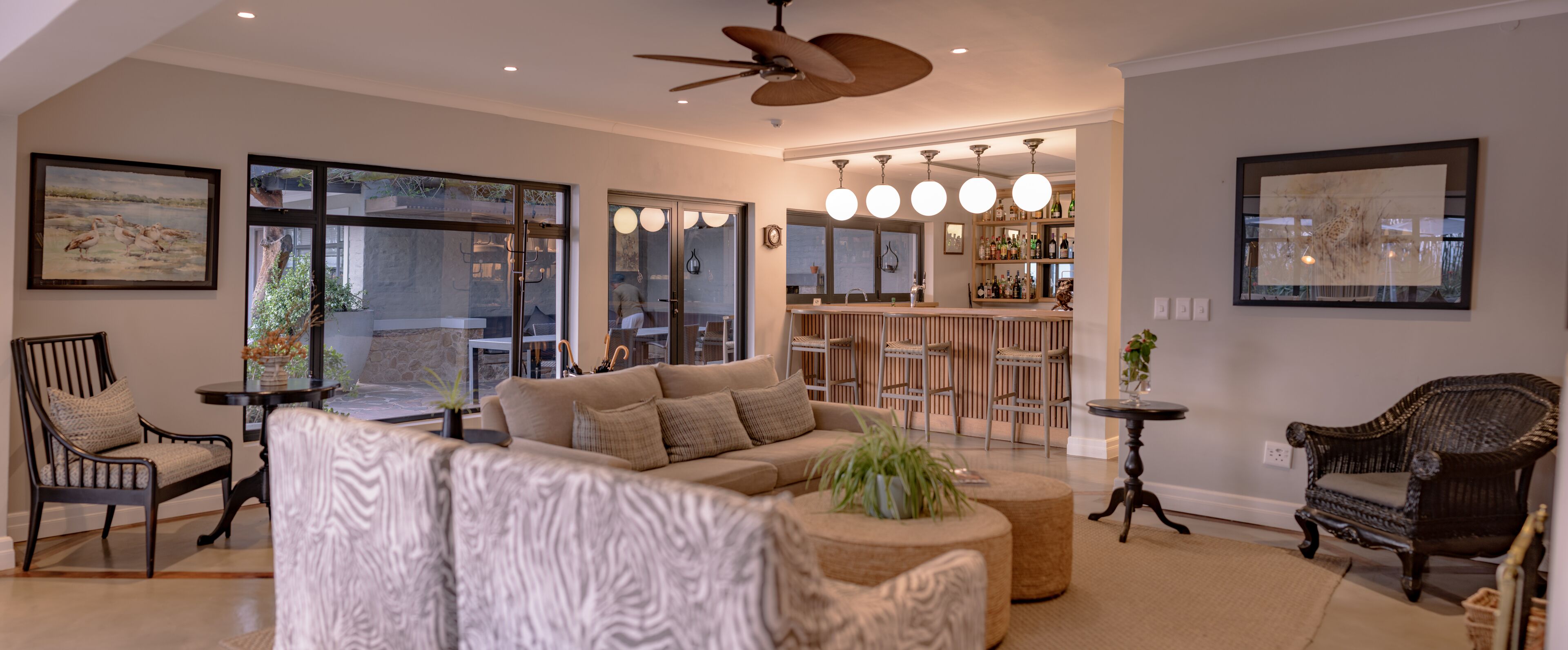 En rummelig opholdsstue med en stor sofa, et spiseområde med bar og udsigt til det fri.