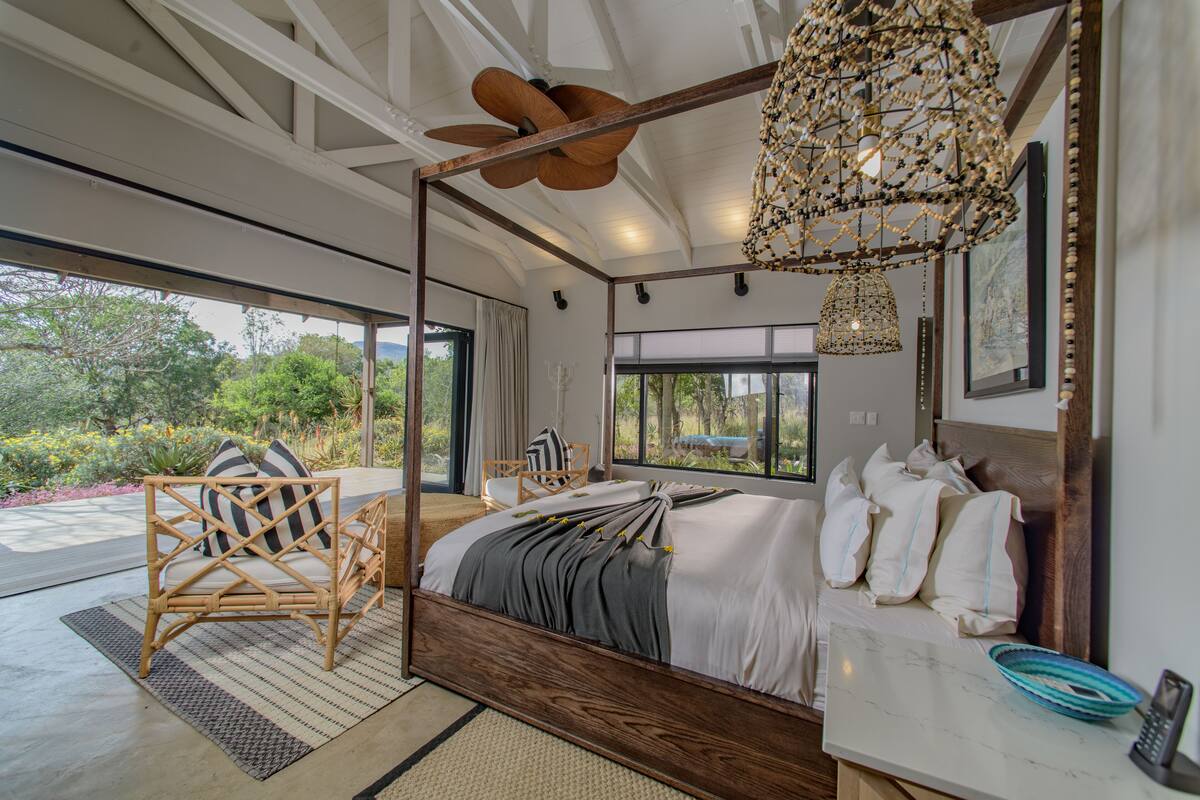 A spacious bedroom with a large bed, a wooden chair, and a view of the outdoors.