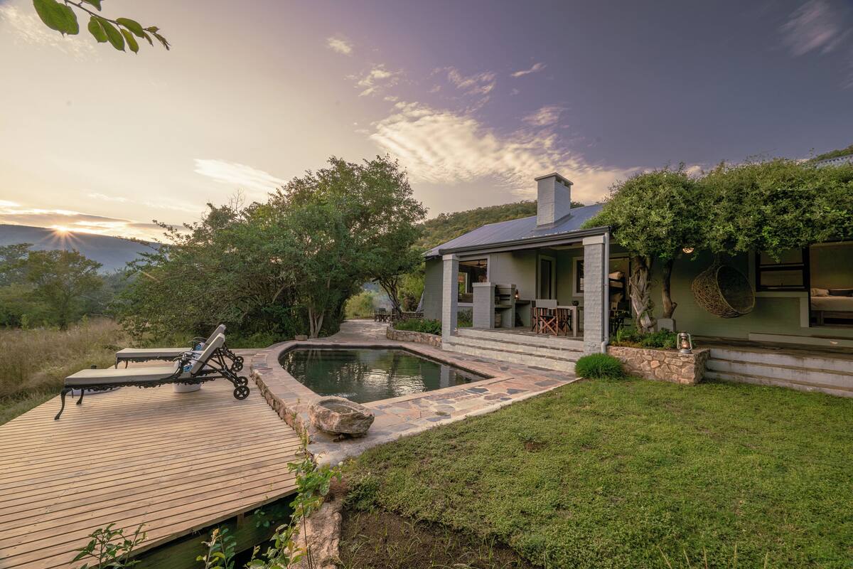 A house with a swimming pool, a wooden deck, and a garden.