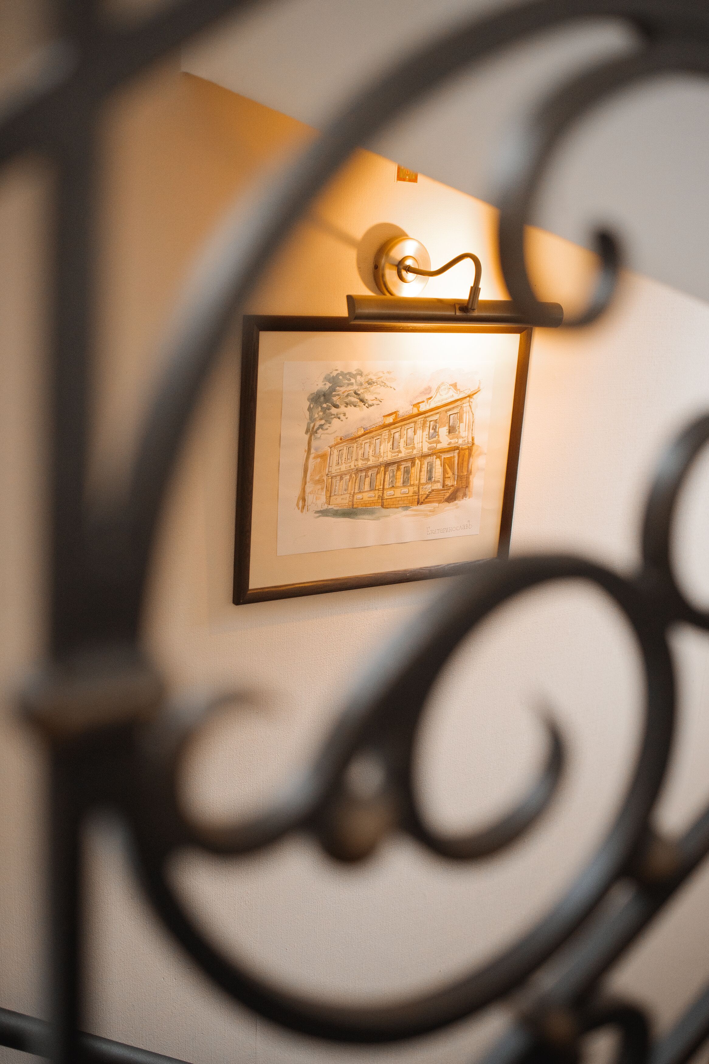 A framed architectural drawing on a wall, with a metal decorative element in the foreground.