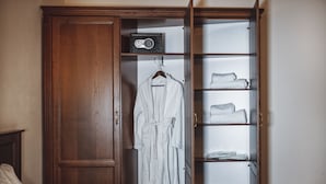 A wooden wardrobe with a hanging robe and shelves containing folded towels. - Ekaterinoslav (Dnipro)