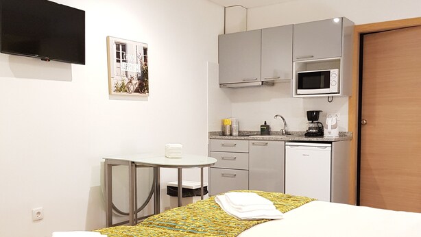 A hotel room with a bed, a small table, a microwave, and a TV. - Apartamento À Francos Metro 1 (Porto)