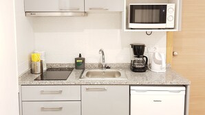 A compact kitchen with a microwave, coffee maker, and a sink. - Apartamento À Francos Metro 1 (Porto)