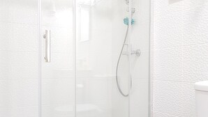 A glass-enclosed shower stall with a handheld showerhead and a wall-mounted faucet. - Apartamento À Francos Metro 1 (Porto)