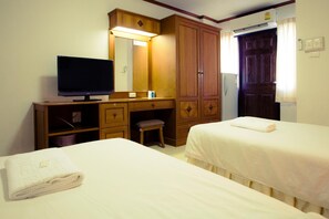 Ett hotellrum med två sängar, ett skrivbord med en tv, en spegel och en garderob.