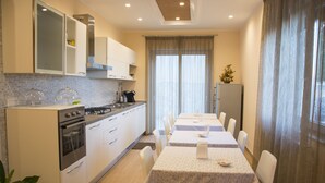 Una cocina moderna con armarios blancos, una estufa y un comedor con una mesa lista para dos.