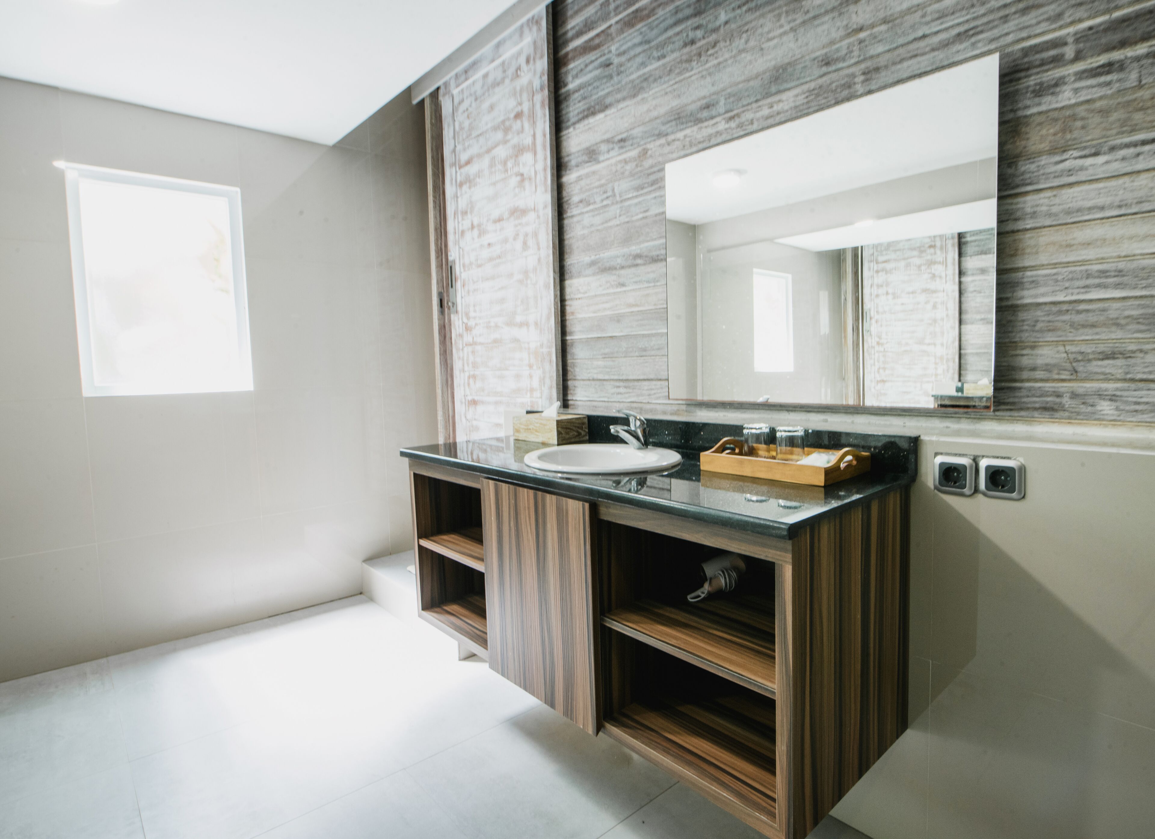 A modern bathroom with a wooden vanity, a sink, and a large mirror.