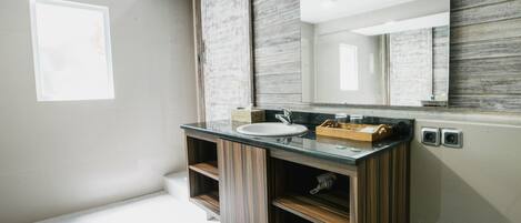 A modern bathroom with a wooden vanity, a sink, and a large mirror.