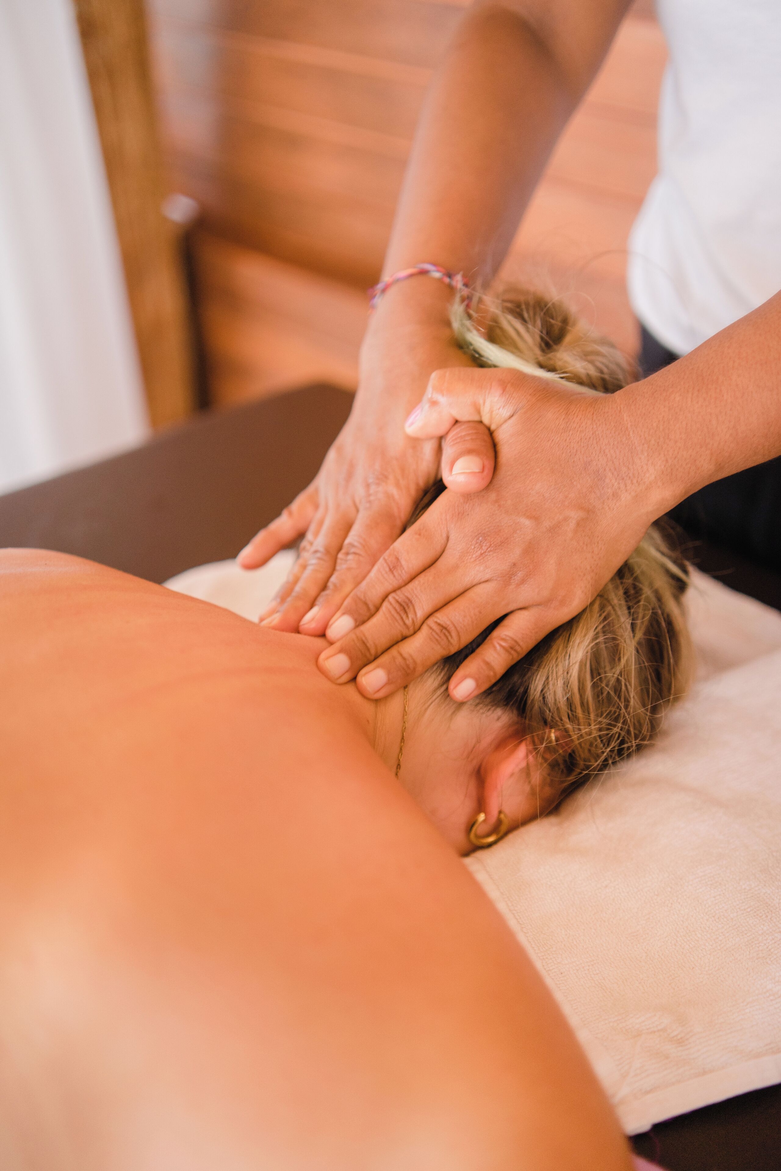 A massage therapy session with a person lying face down on a massage table, receiving hands-on pressure on the back.