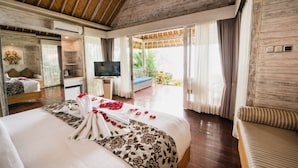 Una habitación de hotel con una cama grande, televisión, escritorio y balcón con cortinas.