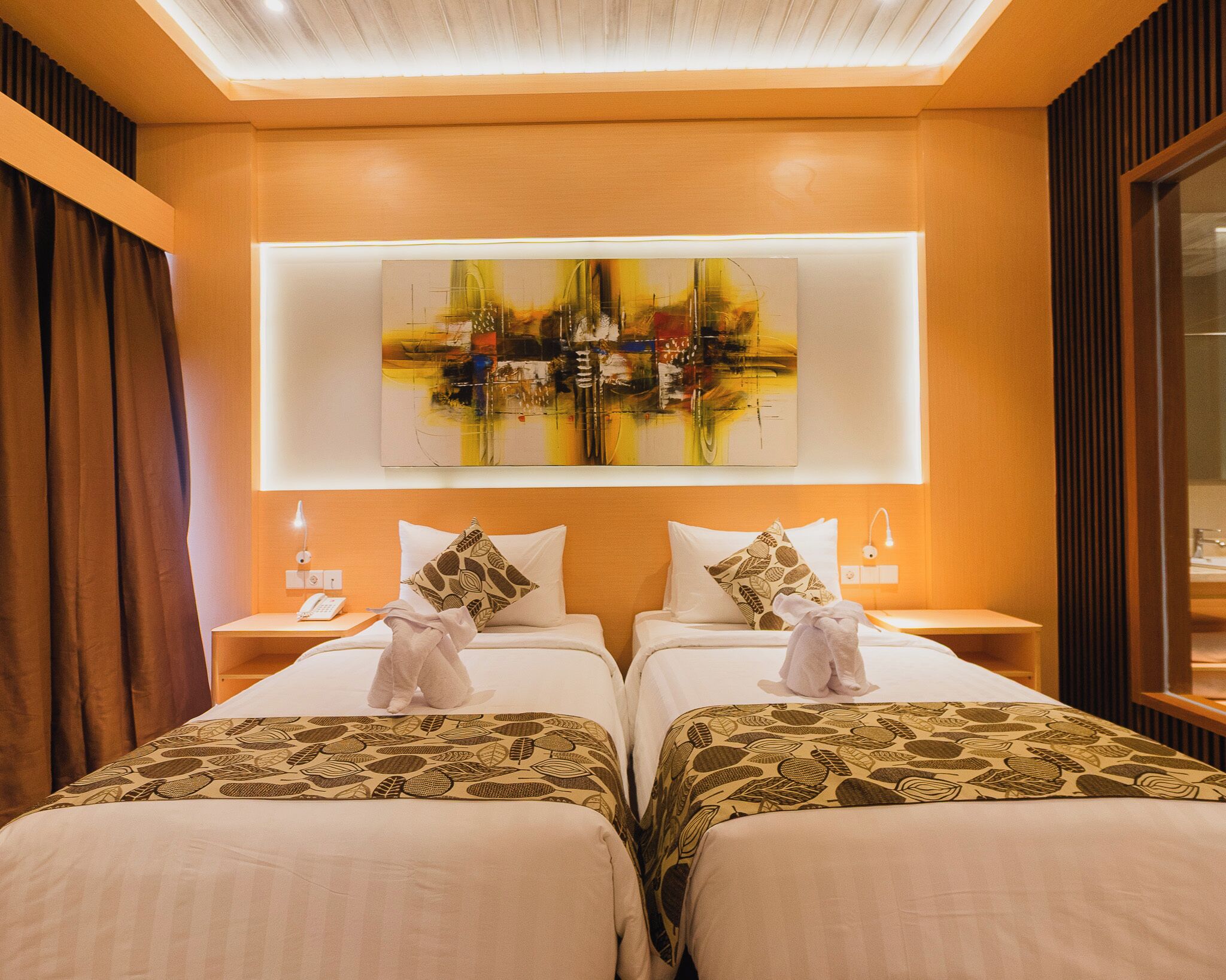 Een hotelkamer met twee bedden, een groot abstract schilderij erboven en een spiegel aan de rechtermuur.