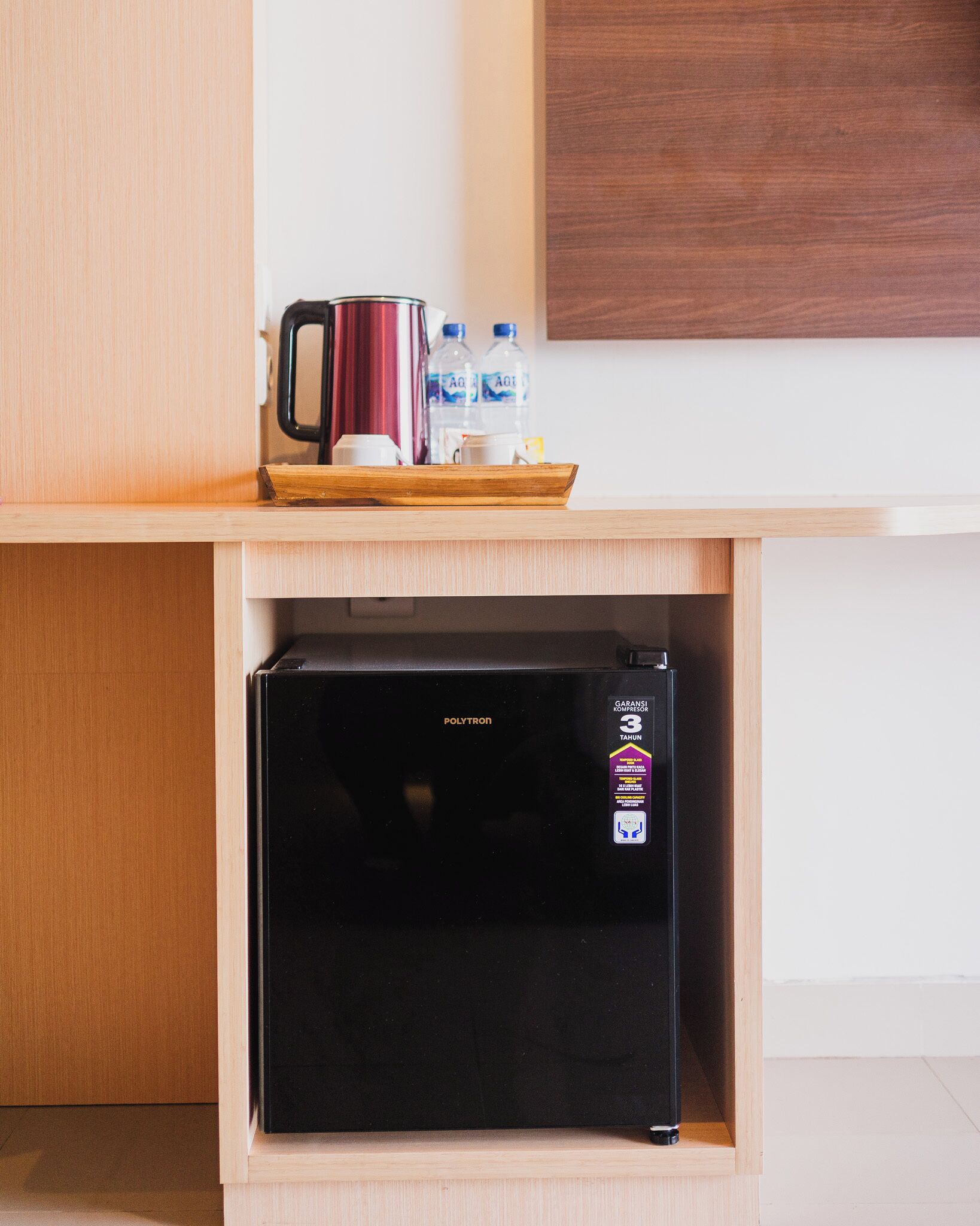 A compact kitchenette with a black refrigerator, a wooden countertop, and a coffee maker.