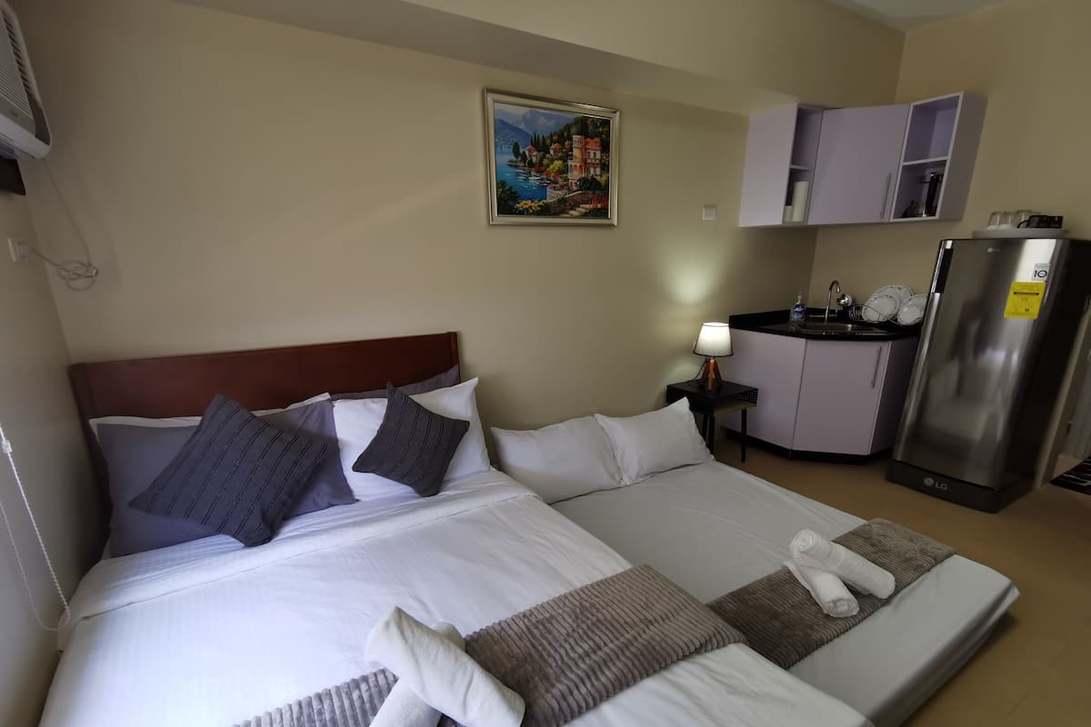 Hotellihuone, jossa on suuri sänky, pieni keittokomero ja taulu seinällä.