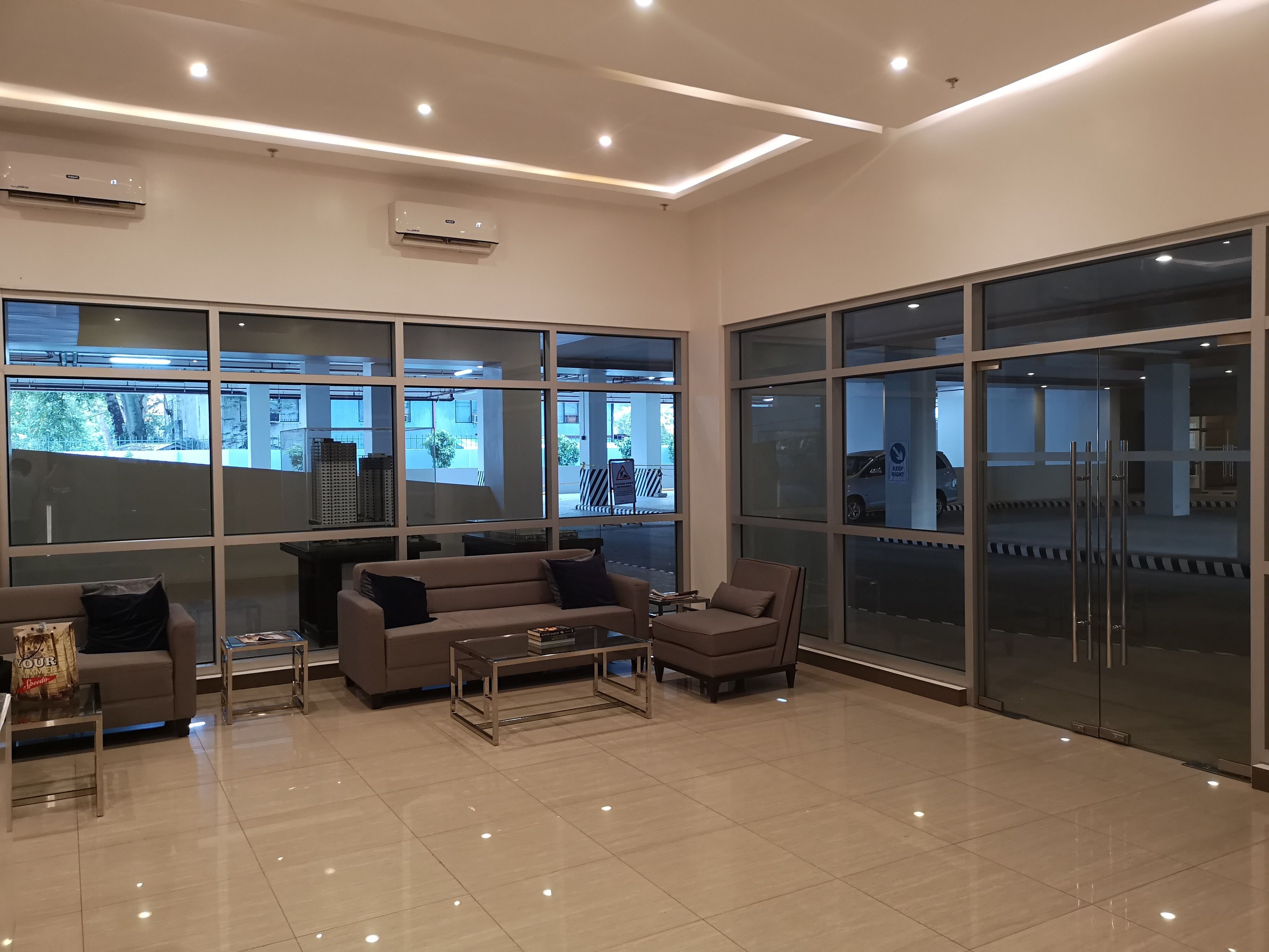 Amplia sala de estar con sofá, sillones y una mesa de centro. Grandes ventanas ofrecen vistas al exterior.