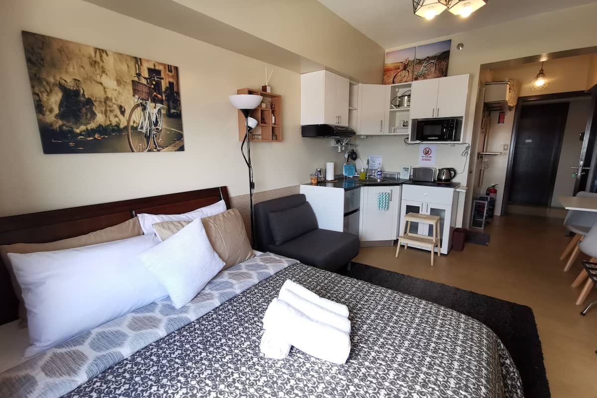Hotellihuone, jossa on sänky, työpöytä, pieni keittiö ja ruokailutila.
