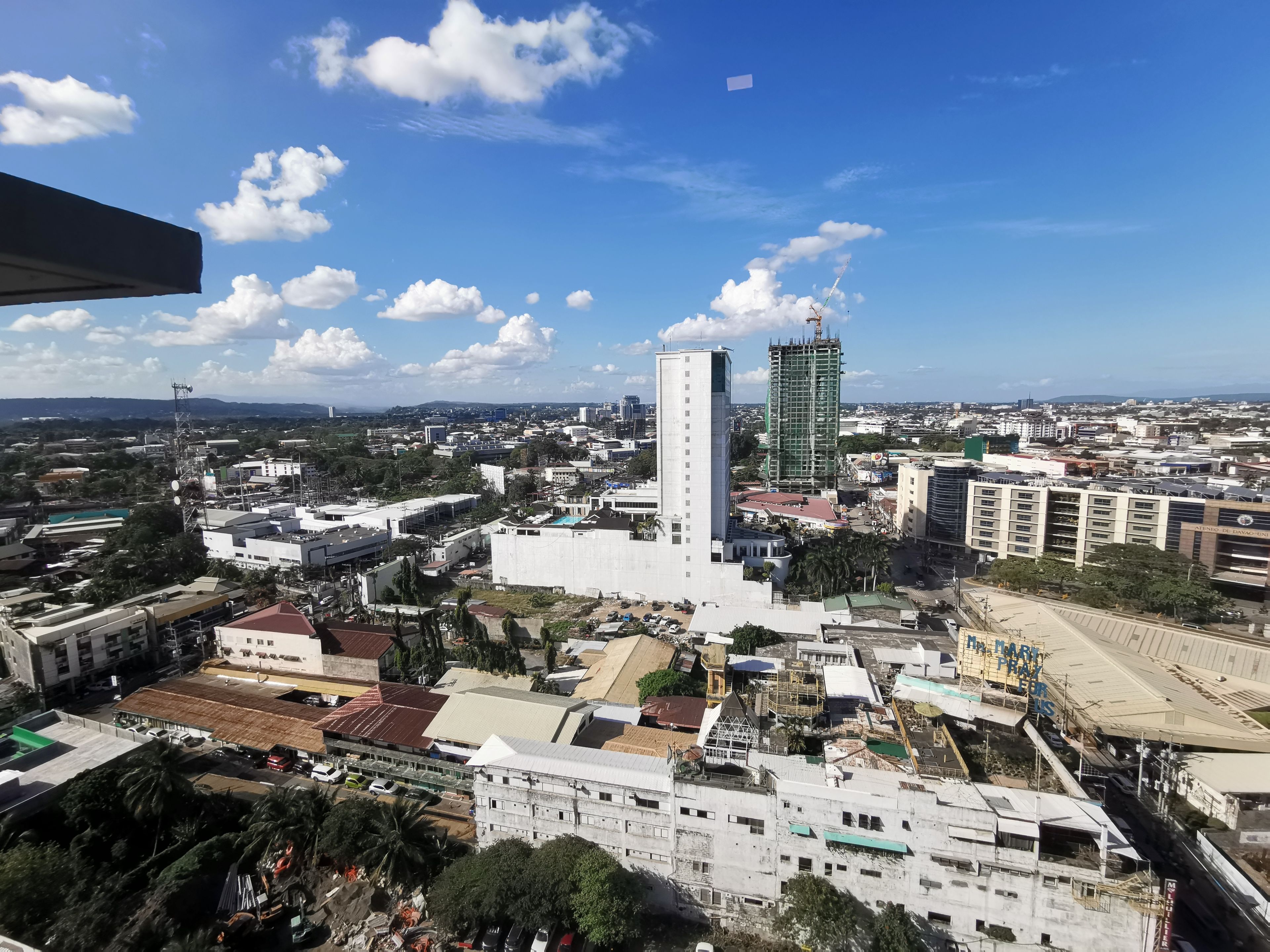 A cityscape with a prominent white building, a construction site, and a clear blue sky.